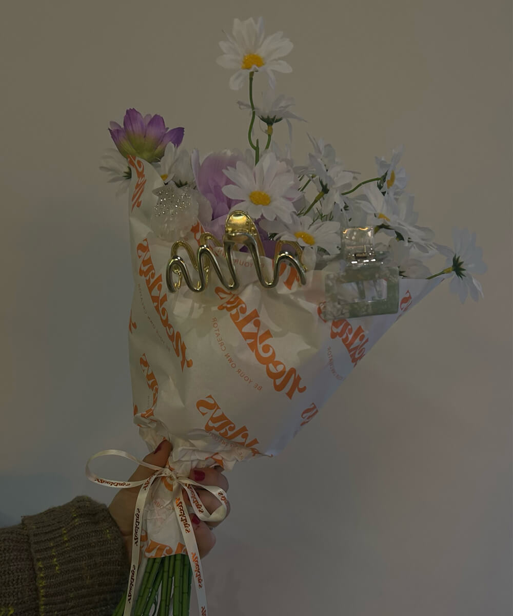 Blumenstrauß eingewickelt in Necklays Papier und Haarspangen